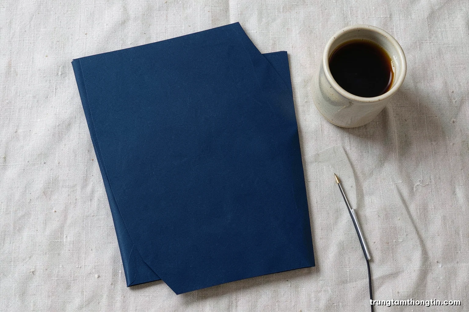 Top-down view of a tidy desk with a closed paper folder, a fingerprint scanner and a ceramic cup, neutral linen background, soft overcast light, beige and slate blue palette